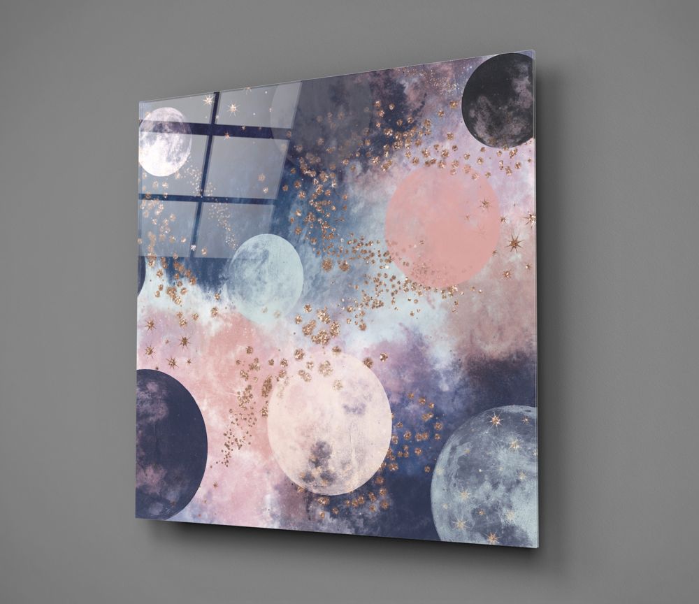 Square glass wall art featuring moons in varying phases against pink, blue, and purple watercolor backgrounds with gold sparkle accents, displayed at an angle against gray wall.