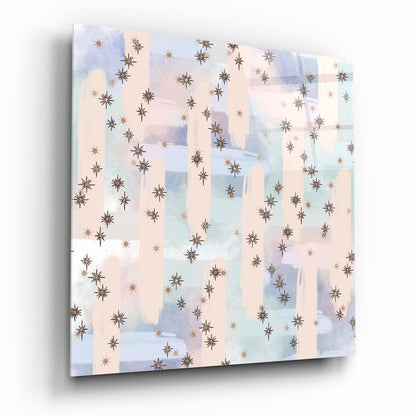 Angled perspective of glass wall art featuring brown and copper stars scattered across soft watercolor washes in cream, blue, and lavender.