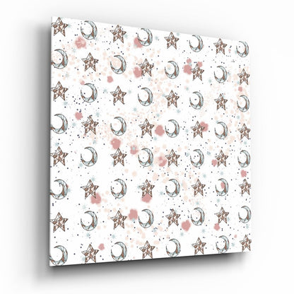 Angled perspective view of glass wall art displaying repeating pattern of brown stars and crescent moons with pink and blue watercolor splashes on white background.