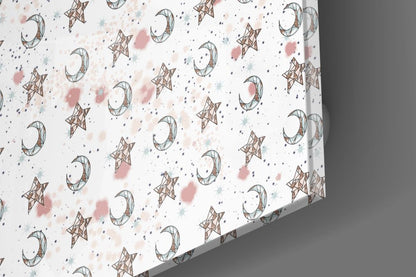 Close-up angled view of glass wall art showing repeating pattern of brown moons and stars with pink and blue watercolor splashes on white background.