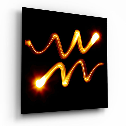 Glowing neon-style wavy lines in golden yellow and orange forming an Aquarius symbol on black glass, photographed at an angle showing the panel's depth and shadow.