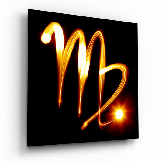 Glowing amber neon Virgo symbol on black glass panel, angled three-quarter view showing depth and luminous effect.