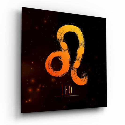 Square glass panel displaying orange and yellow Leo zodiac symbol on black background with scattered golden sparkles, viewed at an angle.