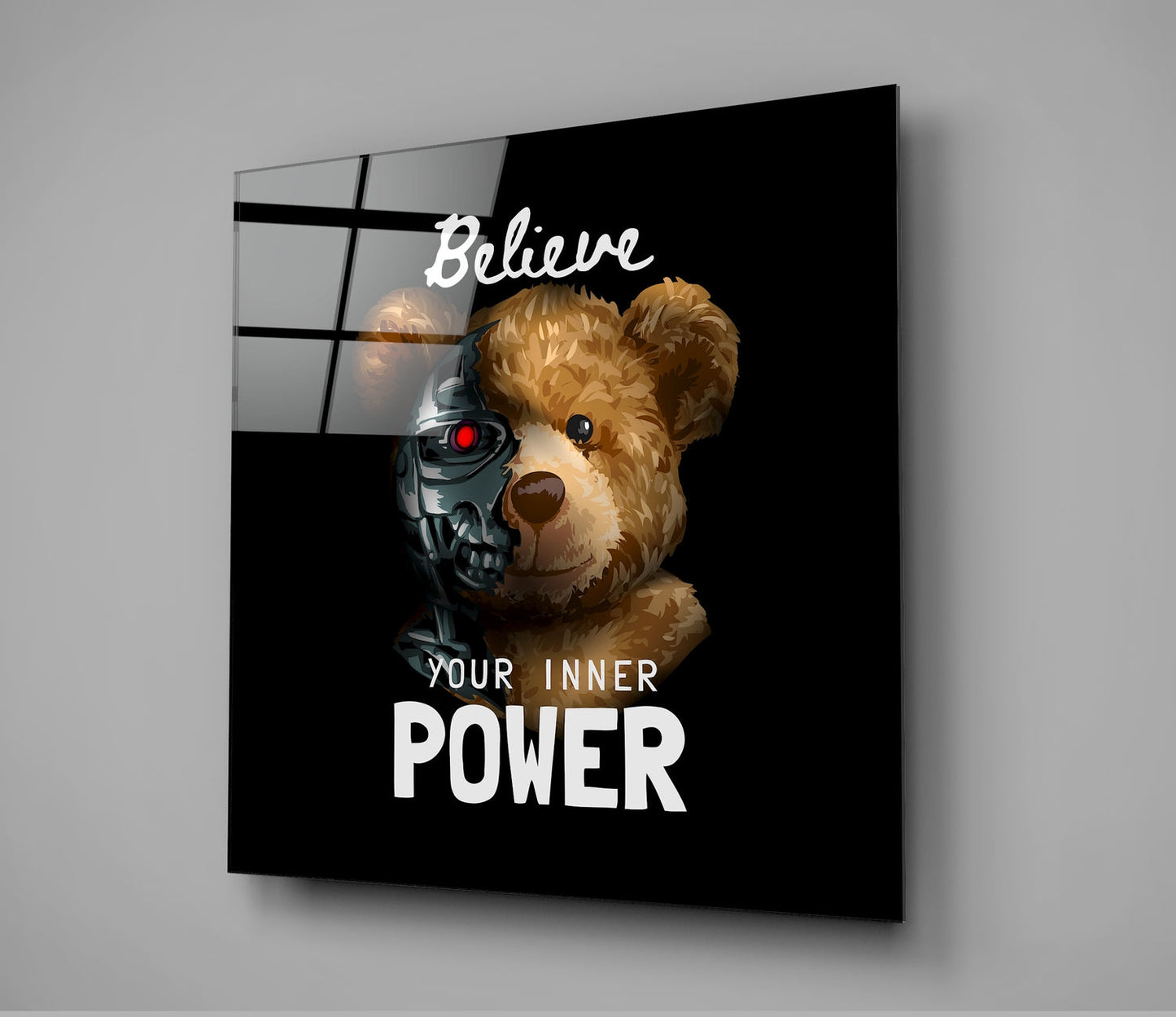 Black glass wall art displaying a brown teddy bear with a robotic skull overlay and text reading "Believe Your Inner Power," shown at an angled perspective.