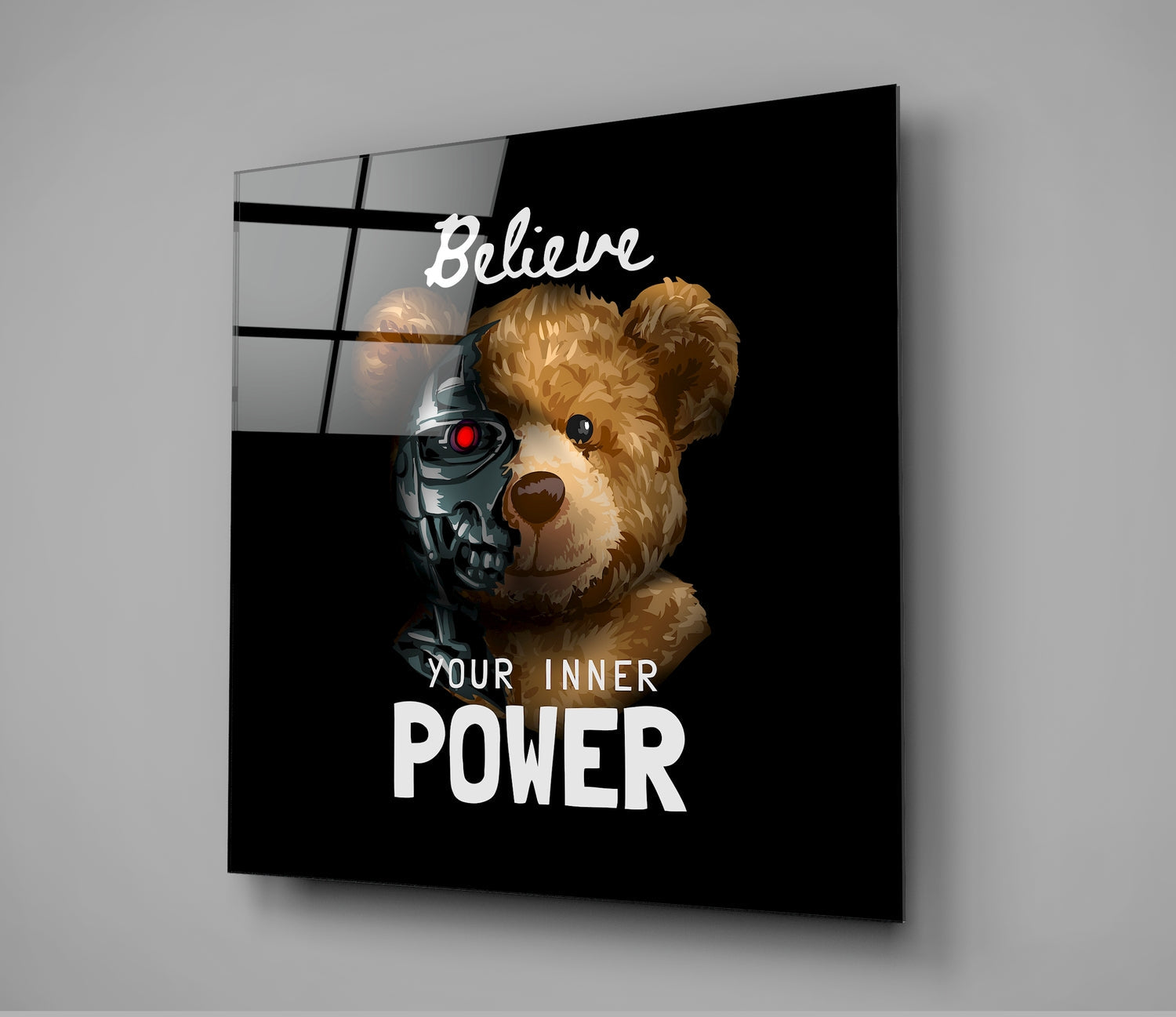Black glass wall art displaying a brown teddy bear with a robotic skull overlay and text reading "Believe Your Inner Power," shown at an angled perspective.