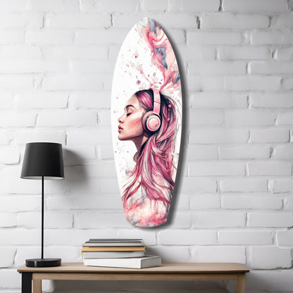 Oval glass wall art featuring a pink-haired woman in profile wearing headphones, displayed above a wooden table with lamp and books against white brick.