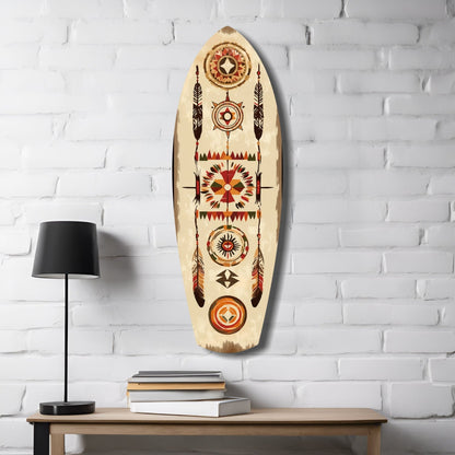 Aztec-patterned wooden surfboard wall art hanging above wooden table with black lamp and stacked books.