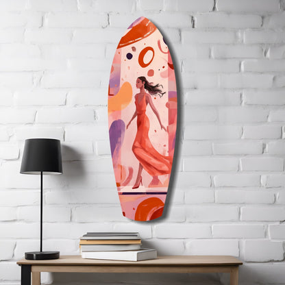 Oval glass wall art featuring illustrated woman in red dress with abstract orange and purple circles on pink background, displayed on white brick wall above wooden table with lamp and books.