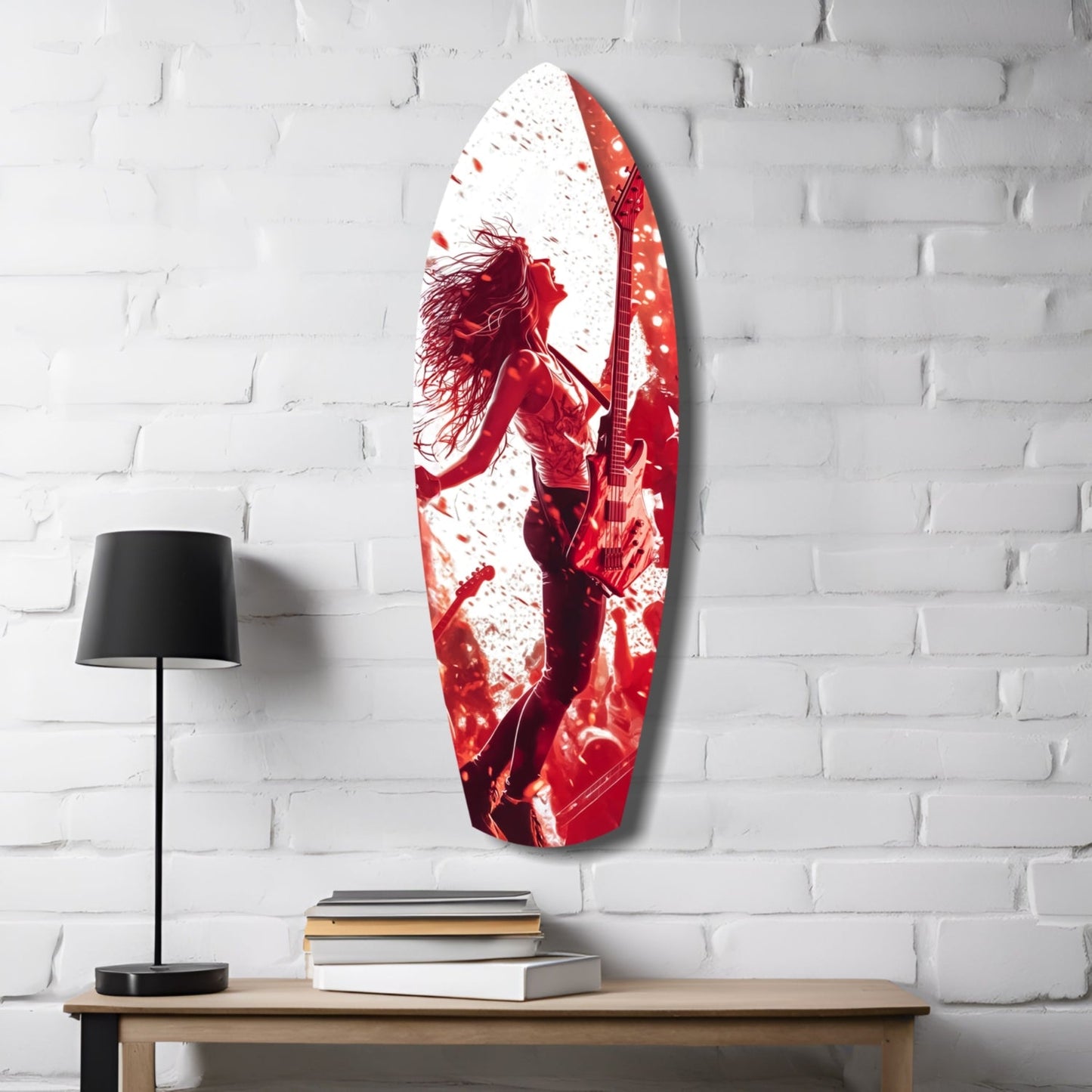 Red and white glass wall art featuring a silhouetted musician with guitar mounted above wooden desk with lamp and books.