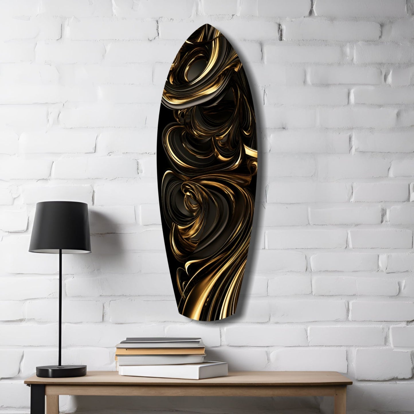 Black and gold swirled glass wall art hanging above wooden table with lamp and stacked books against white brick wall.