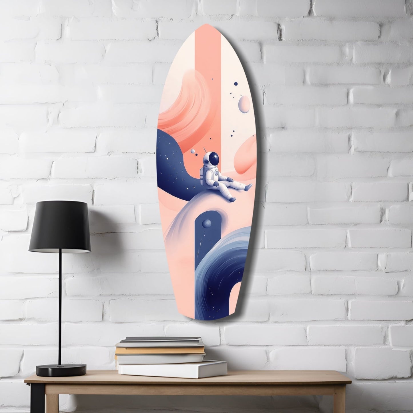 Oval glass wall art featuring an astronaut on a planetary landscape in coral, cream, and navy blue tones, displayed on a white brick wall above a wooden desk with lamp and books.