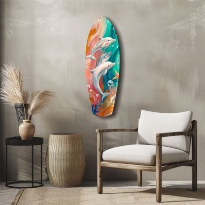 Colorful glass surfboard wall art depicting three dolphins leaping through turquoise and coral ocean waves, displayed in a modern living room setting.