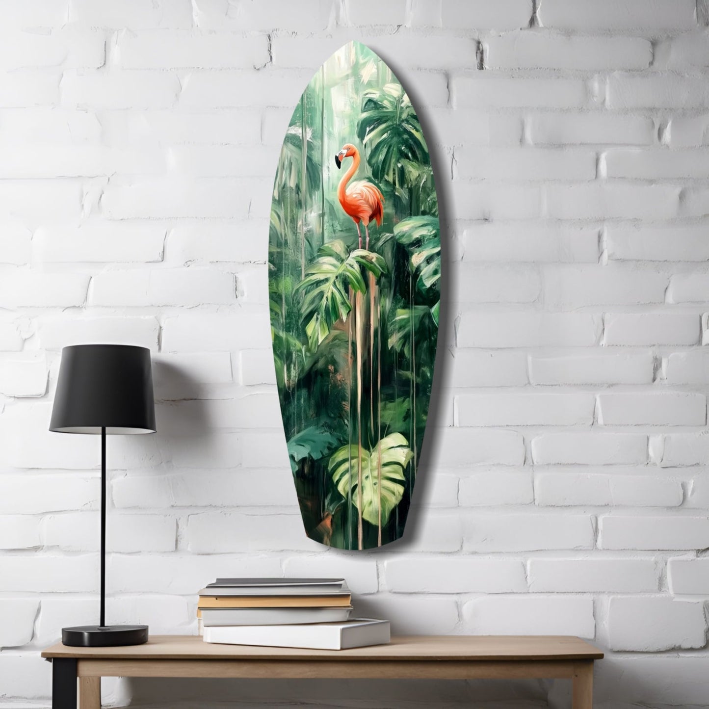 Oval glass wall art depicting a pink flamingo among green tropical foliage, displayed on white brick wall above wooden desk with lamp and books.