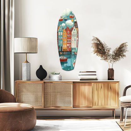Coastal village glass wall art in boat shape displays colorful waterfront houses, boats, and clouds above wooden mid-century furniture.