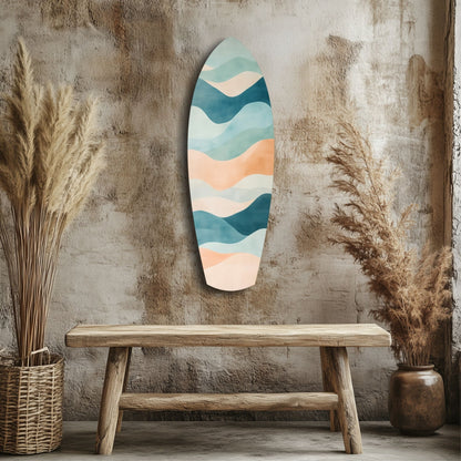 Modern surfboard-shaped wall art with layered wave design in teal, cream, and peach tones displayed above wooden bench in rustic interior.