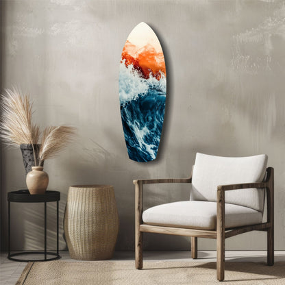 Surfboard-shaped glass wall art displaying ocean waves in blue and white with orange-red sunset tones, displayed in a minimalist room setting.