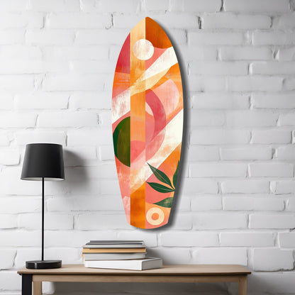 Oval glass wall art with abstract geometric design in orange, coral, red, and green tones hanging on white brick wall above wooden table with lamp and books.