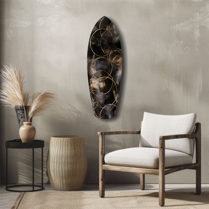 Black glass wall art with gold circular wire overlay displayed above wooden chair in modern interior setting.