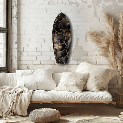 Black glass teardrop wall art with gold circular wire details displayed above white bedding in minimalist bedroom setting.