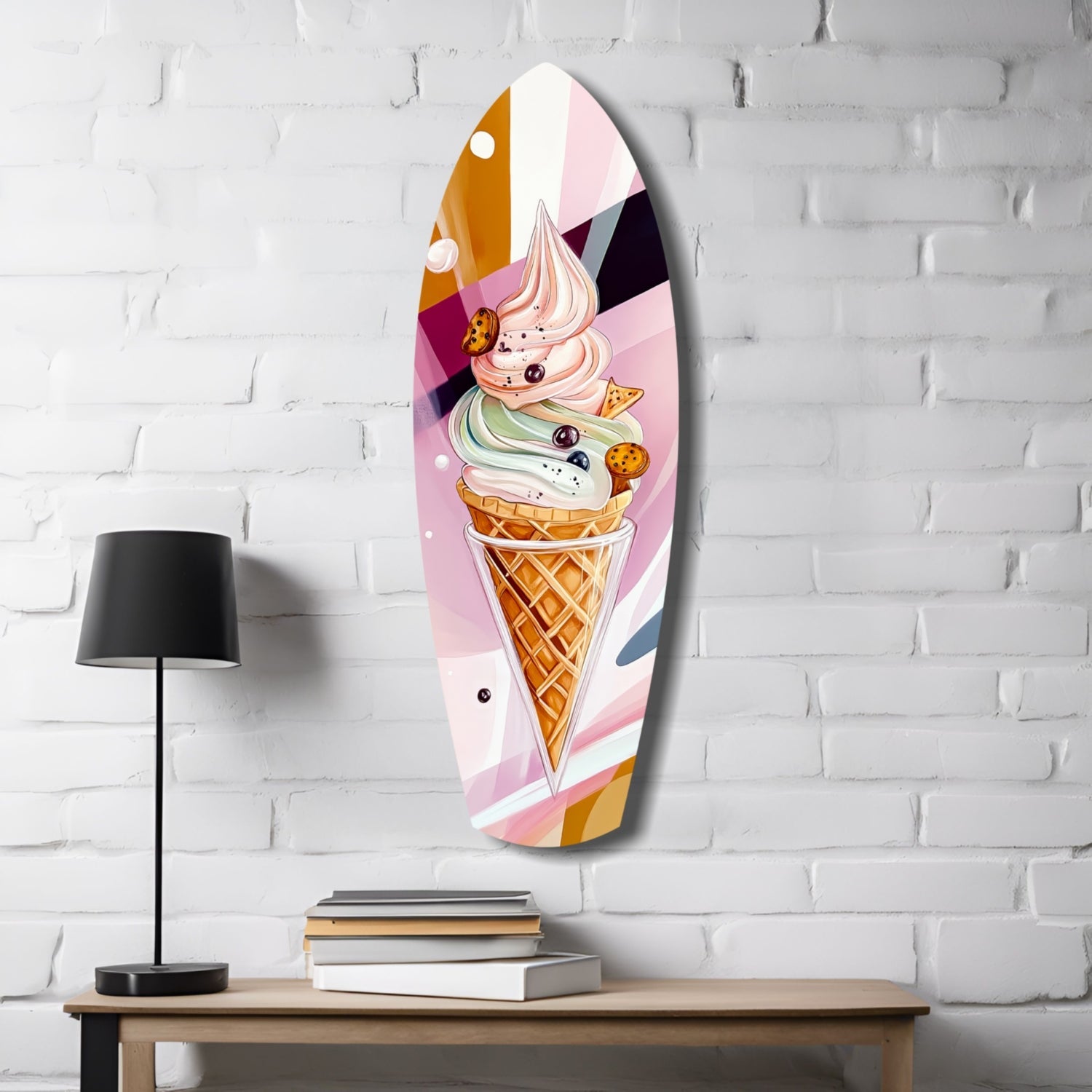 Oval glass wall art featuring a colorful ice cream cone with pink, white, and tan swirls displayed on white brick wall above wooden desk with lamp and books.
