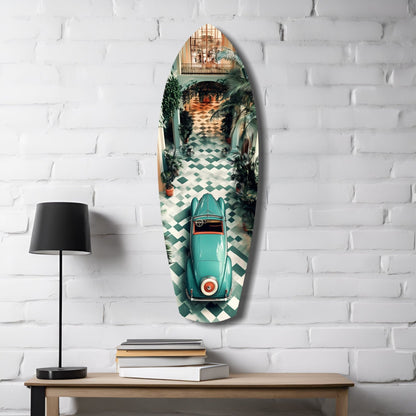 Turquoise vintage car surfboard-shaped glass wall art displayed on white brick beside wooden desk with black lamp and stacked books.