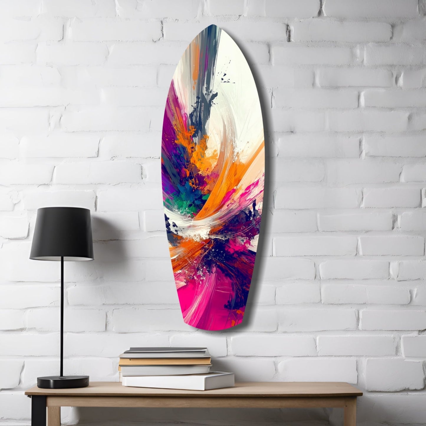 Oval glass wall art with vibrant abstract paint strokes in magenta, orange, blue, and purple displayed above a wooden desk with lamp and books.