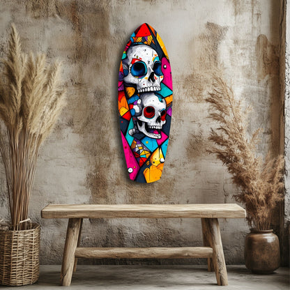Colorful glass wall art featuring two stacked skulls with vibrant geometric patterns displayed above a wooden bench in a textured room setting.