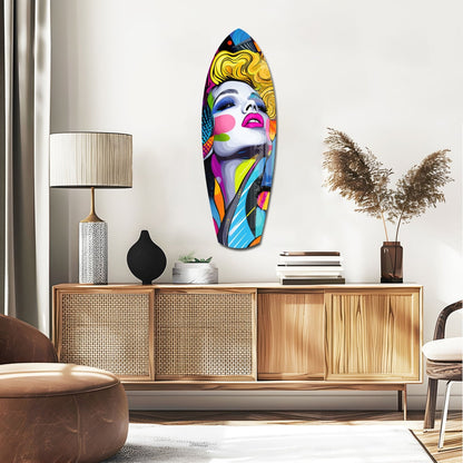 Colorful pop art glass wall art featuring a woman's face with blonde hair and vibrant multicolored geometric patterns displayed above a wooden sideboard.