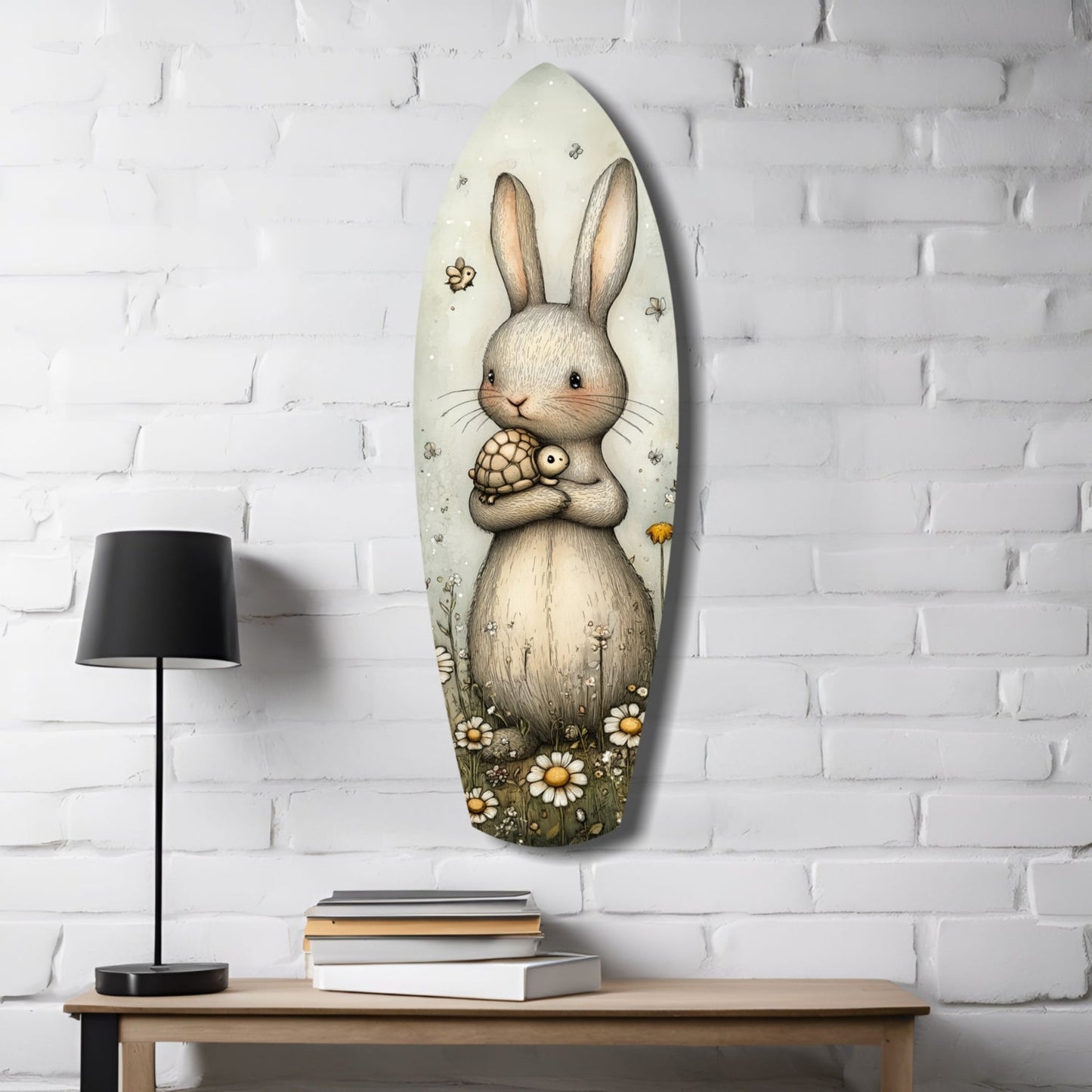 Oval glass wall art depicting a cream-colored rabbit holding a small turtle, surrounded by daisies, displayed on white brick wall above wooden desk with lamp and books.
