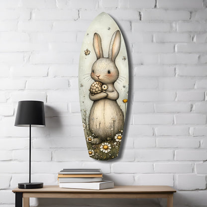 Oval glass wall art depicting a cream-colored rabbit holding a small turtle, surrounded by daisies, displayed on white brick wall above wooden desk with lamp and books.
