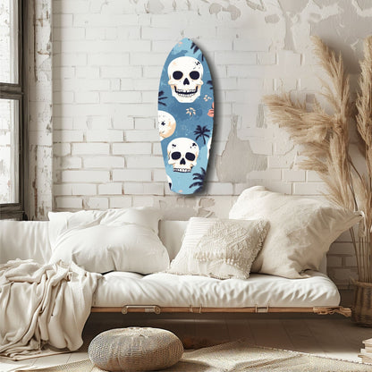 Surfboard-shaped glass wall art with blue background, white skulls, and tropical palm tree designs hanging above a cream-colored bed in a minimalist bedroom.
