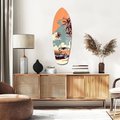 Surfboard-shaped glass wall art displaying vintage 1950s car, palm trees, and orange sunset sky, mounted above wooden mid-century sideboard in modern living room.