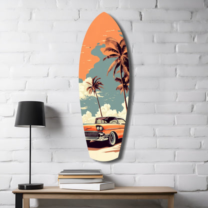 Surfboard-shaped glass wall art displaying retro beach scene with orange sky, palm trees, vintage orange car, and cream sand, mounted on white brick wall beside lamp and books.