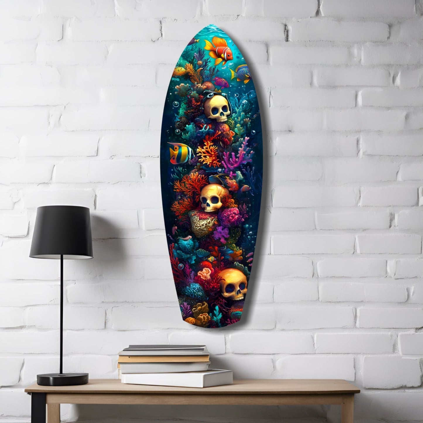 Oval glass wall art hanging on white brick wall above wooden table with lamp and books, featuring colorful coral, tropical fish, and golden skulls on dark background.