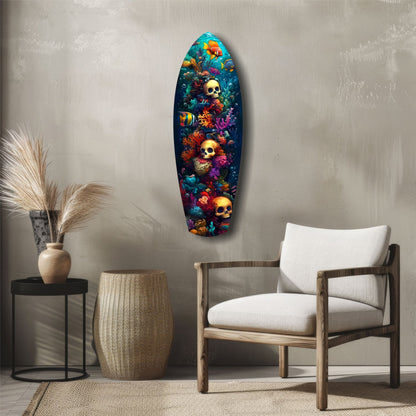 Surfboard-shaped glass wall art with colorful coral, tropical fish, and golden skulls displayed in a minimalist living room setting.