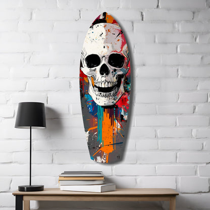 Colorful street art skull glass panel mounted on white brick wall above wooden desk with lamp and books.