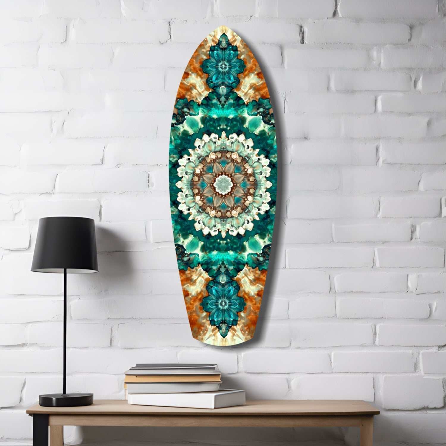 Oval glass wall art with teal, emerald, and orange kaleidoscopic floral design displayed above wooden desk with lamp and books.