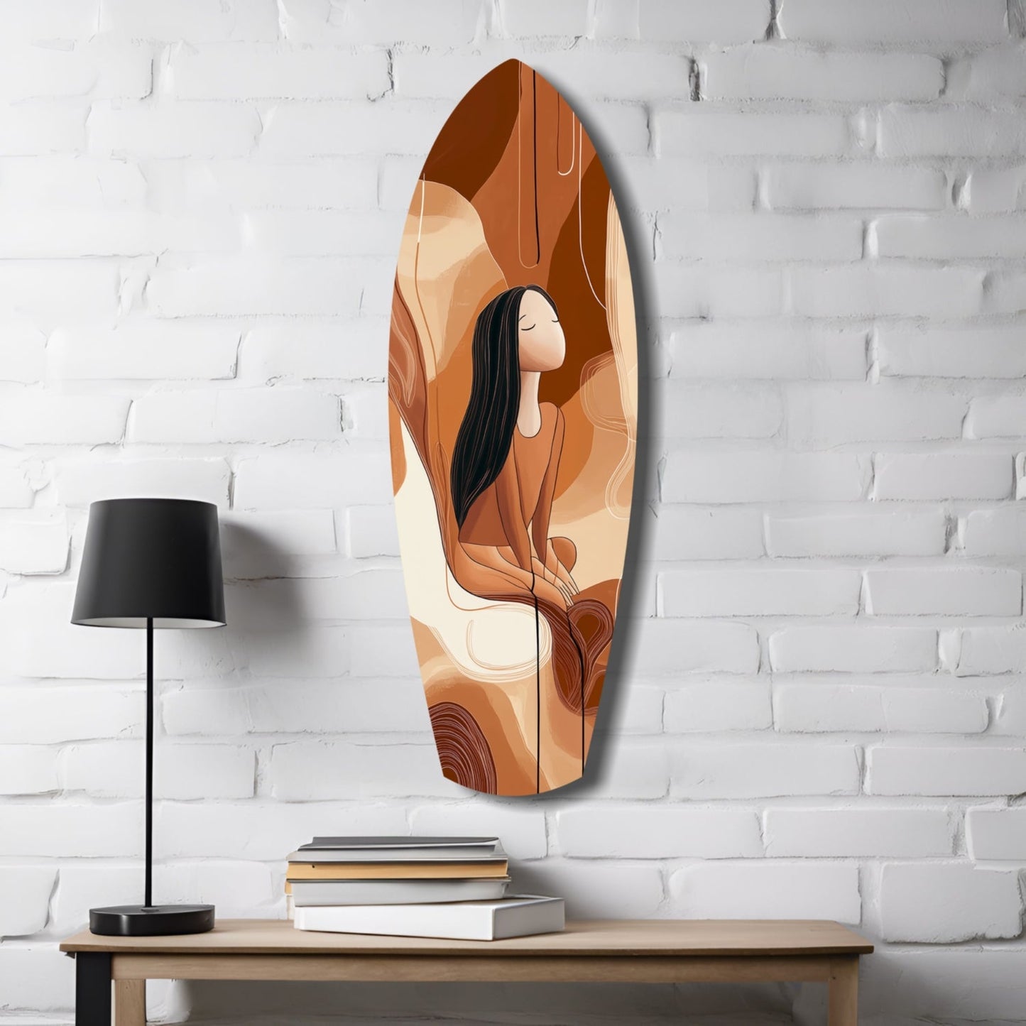 Oval glass wall art featuring a woman with long black hair in warm orange and brown tones, displayed on white brick wall above wooden table with lamp and books.