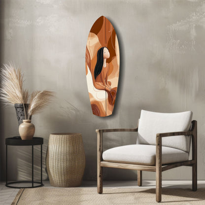 Abstract glass wall art in warm terracotta and cream tones depicting a seated figure, displayed above wooden furniture in a minimalist interior setting.