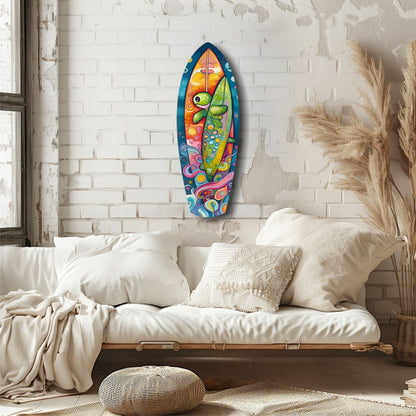 Colorful surfboard-shaped glass wall art with sea turtle design hanging above a cream-colored bed in a minimalist bedroom.