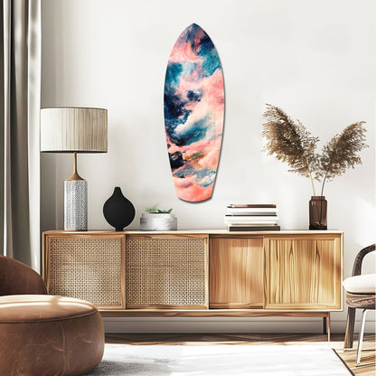 Surfboard-shaped glass wall art with pink, blue, and teal abstract cloud patterns displayed above a wooden mid-century credenza in a modern living room.