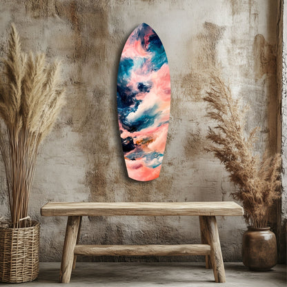 Surfboard-shaped glass wall art with pink, blue, and teal abstract cloud patterns displayed above wooden bench in minimalist room.