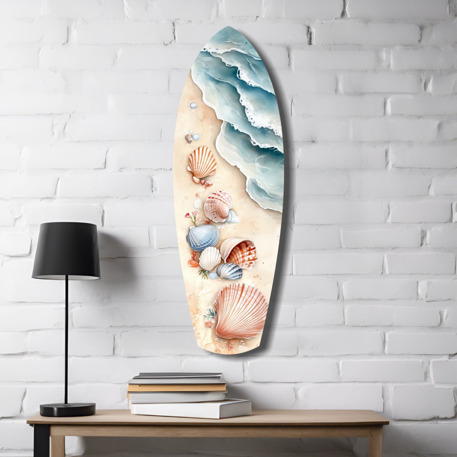 Surfboard-shaped glass wall art mounted on white brick, featuring layered ocean waves, seashells, and sand-colored beach design with black lamp and books below.