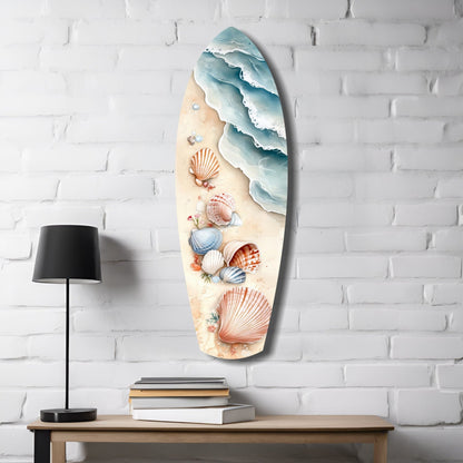 Surfboard-shaped glass wall art mounted on white brick, featuring layered ocean waves, seashells, and sand-colored beach design with black lamp and books below.