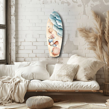 Surfboard-shaped glass wall art featuring layered blue waves and colorful seashells on cream background, displayed above white bedding in coastal bedroom setting.