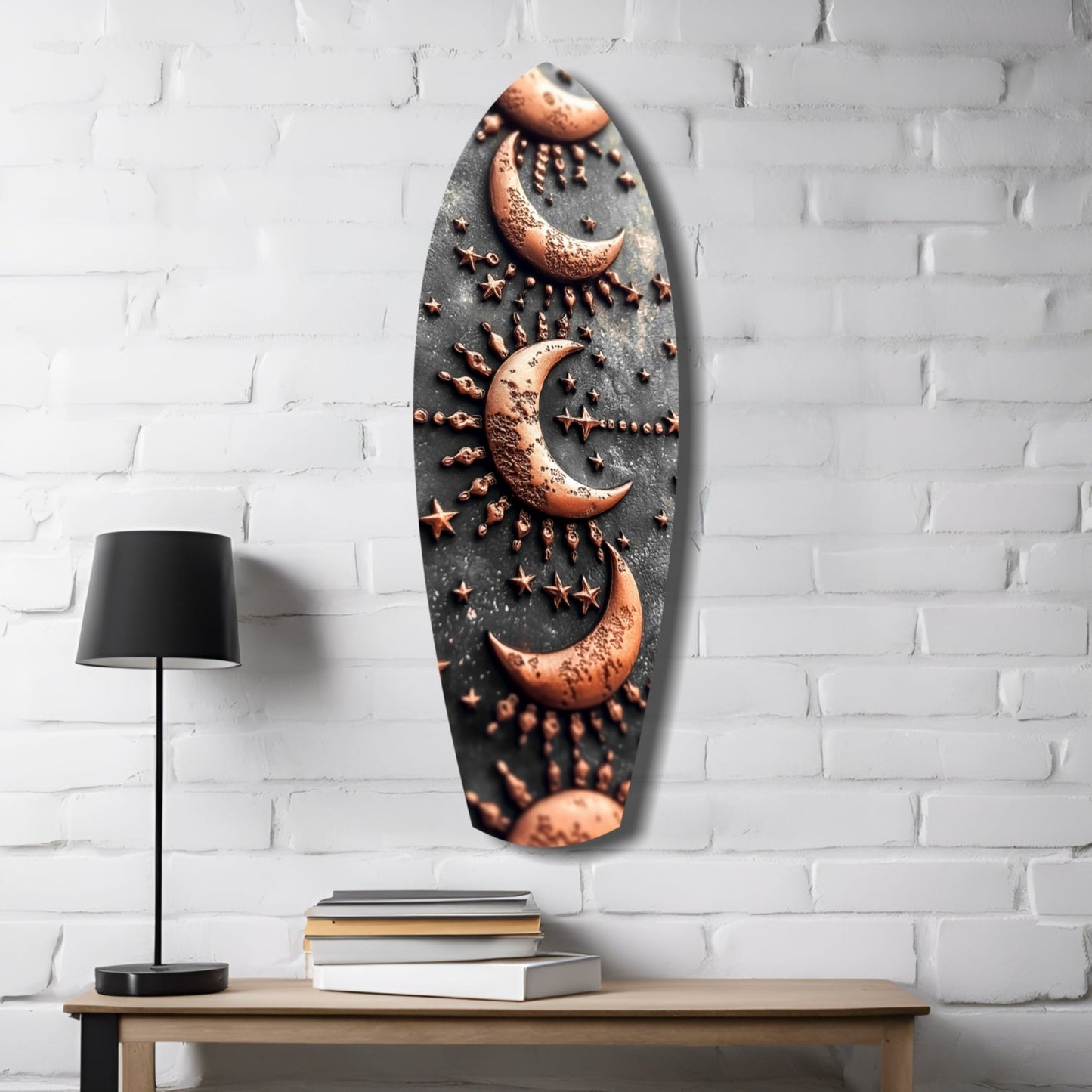 Oval glass wall art featuring copper moons and stars on dark textured background, displayed above wooden table with lamp and books.
