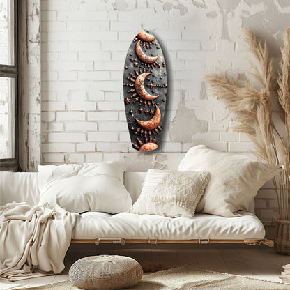Dark oval glass wall art with copper crescent moons and dotted patterns displayed above a cream bedroom daybed.