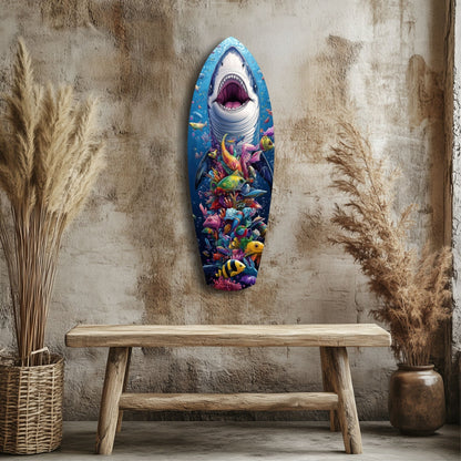 Shark-shaped glass wall art with colorful coral reef fish displayed above wooden bench against textured beige wall.