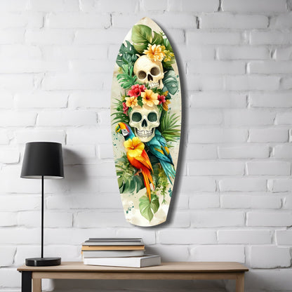 Oval glass wall art featuring two skulls surrounded by tropical flowers, parrots, and green foliage on white brick wall above wooden desk.