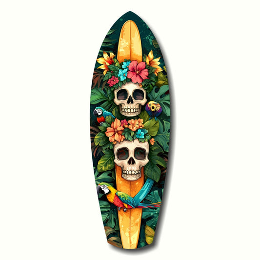 Surfboard-shaped glass art featuring two stacked skulls adorned with colorful flowers and tropical parrots against a dark green foliage background.